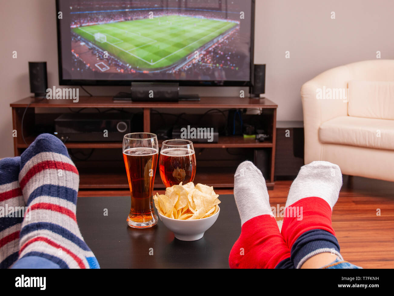 Entspannt Mann lag auf dem Sofa, während Sie Fußballspiel im Fernsehen zu Hause, Bier und Chips auf dem Tisch Stockfoto