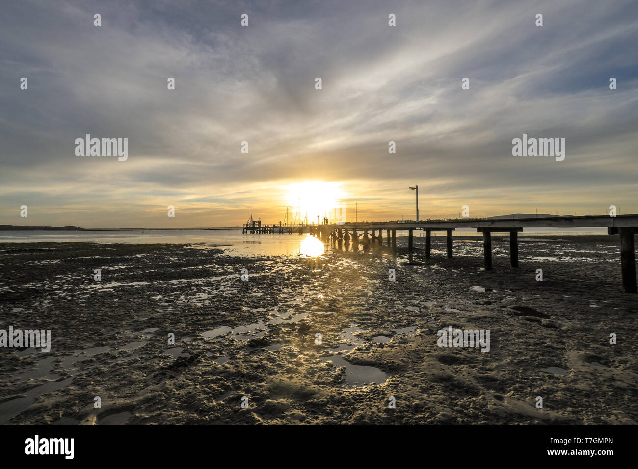 Holzsteg, der zum Sonnenuntergang über dem Meer führt Stockfoto