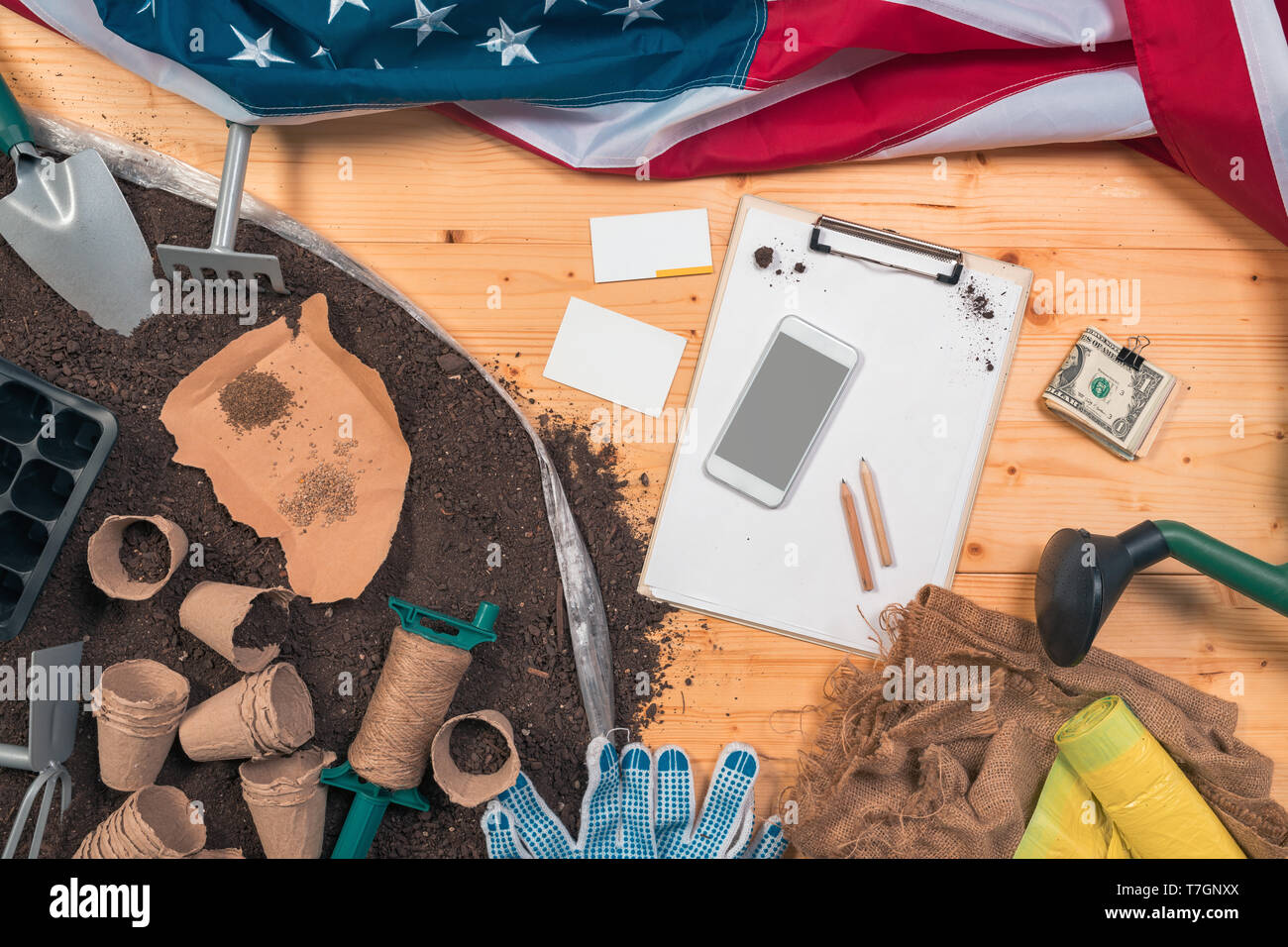 Geld verdienen im ökologischen Landbau, im Garten arbeitende Werkzeuge und Geräte mit Stack des amerikanischen Dollar Stockfoto