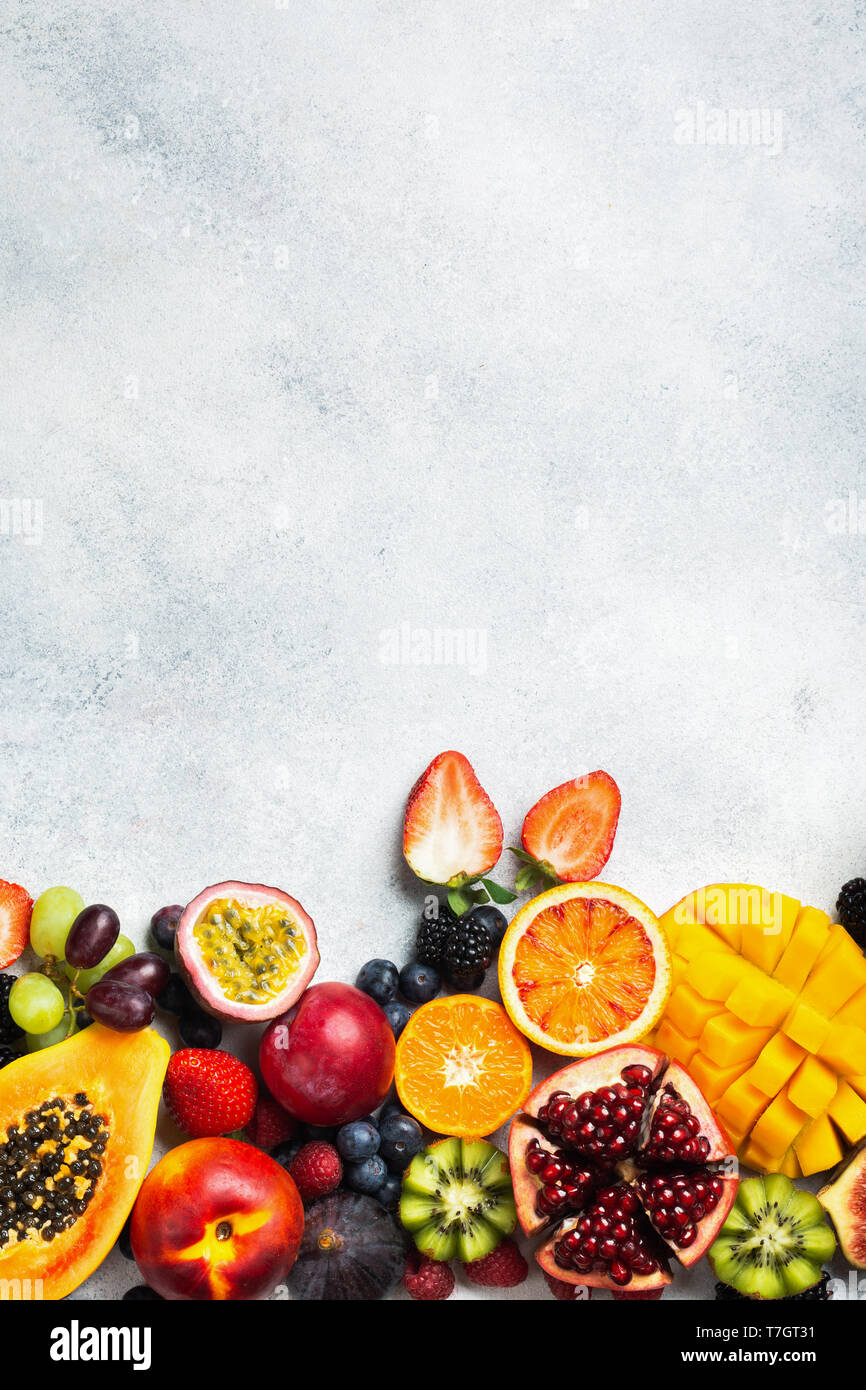 Gesunde Rohstoffe rainbow Früchte Hintergrund, Mango papaya Erdbeeren Passionsfrüchte orangen Beeren auf ovalen Servierteller auf leichte Küche top, Ansicht von oben, Stockfoto