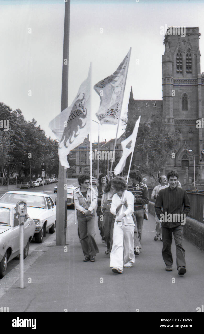 1977 Sydney, Australien: Junge Menschen tragen große Fahnen entlang College Street in Sydney nach einer Demonstration gegen den Uranabbau in Australien. Im Hintergrund kann man die Türme der St.-Mary's-Kathedrale gesehen werden, bevor die endgültige Spire im Jahr 2000 aufgenommen. Stockfoto