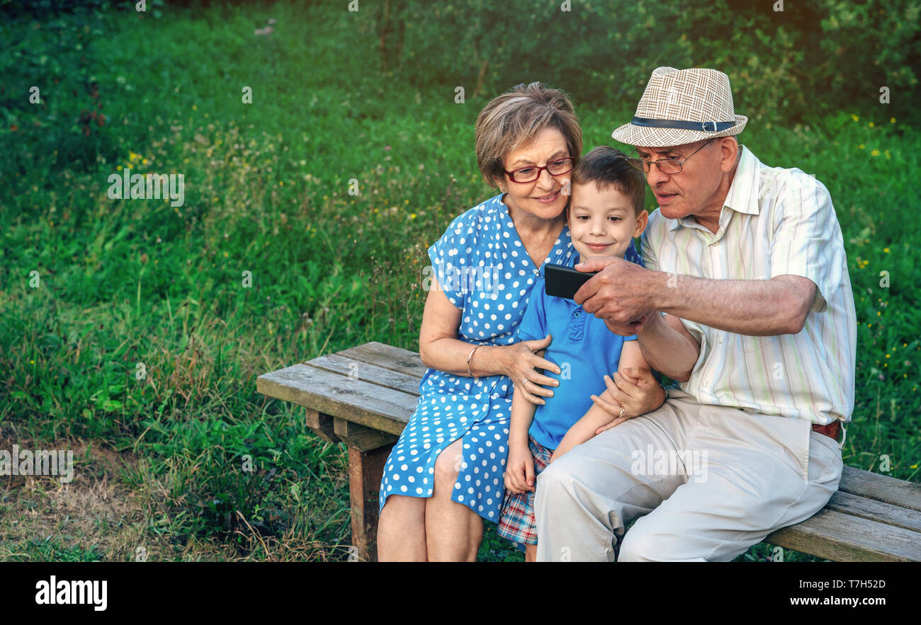 Großvater unter selfie mit Großmutter und Enkel auf einer Bank sitzen Stockfoto
