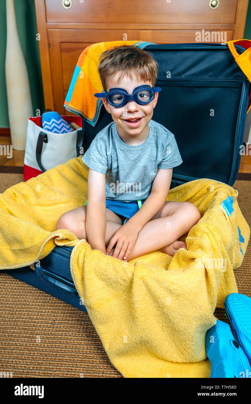 Lustig Junge lächelnd sitzen in einem Koffer bereit, auf Urlaub zu gehen Stockfoto