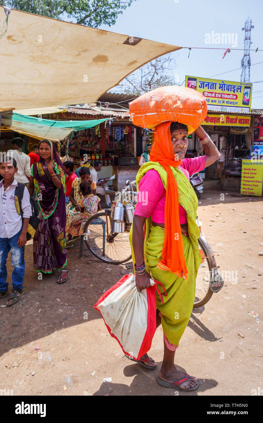 Straßenszene in Dindori Shahpura, eine Kreisstadt in der zentralen indischen Bundesstaat Madhya Pradesh, einem lokalen alte Frau trägt ein Paket auf ihrem Kopf Stockfoto