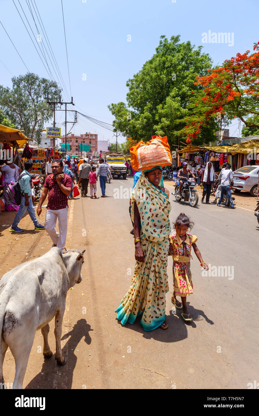 Straßenszene in Shahpura, einer Stadt in der dindori Bezirk der zentralen indischen Bundesstaat Madhya Pradesh, eine lokale Frau trägt Paket auf ihrem Kopf Stockfoto