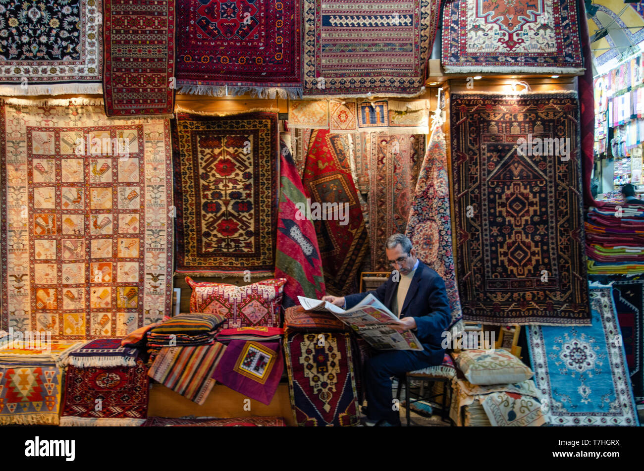 Ein Türkischer Teppich Verkäufer eine Zeitung lesen innerhalb der Grand Bazar, Istanbul, Türkei Stockfoto
