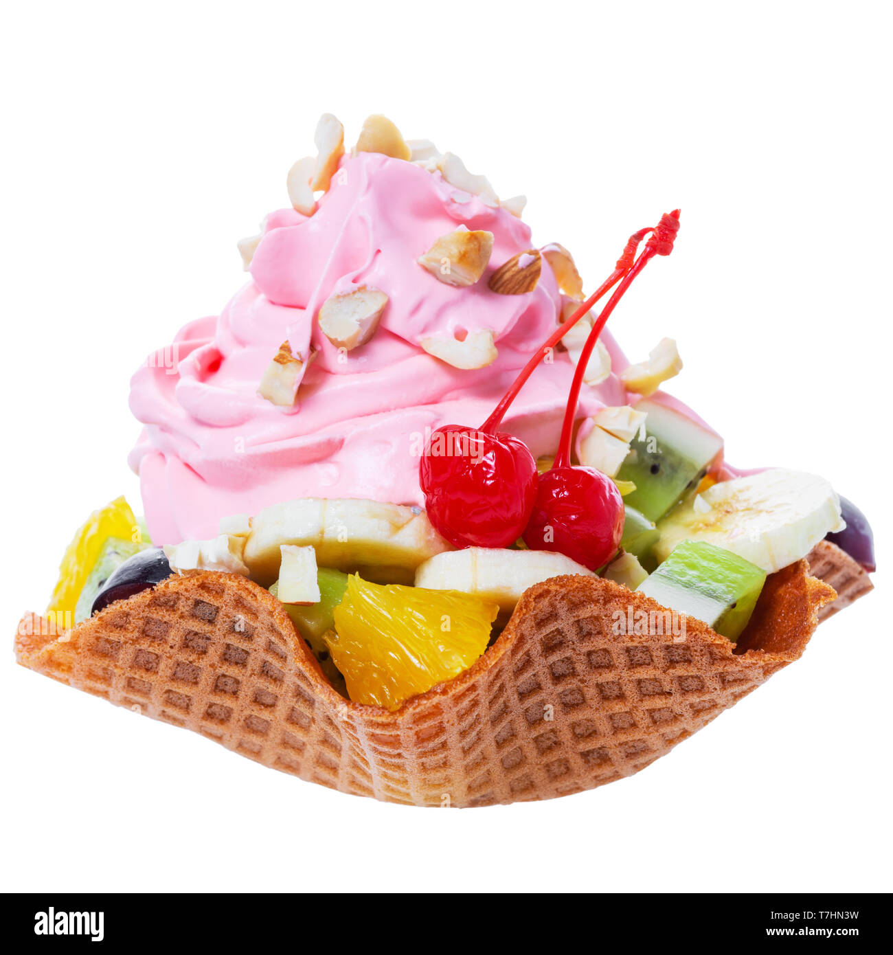 Frisch geschnittene Früchte im Waffle rosa Kegel Schüssel mit Sahne und Nüssen dekoriert maraschino Kirsche ist auf weißem Hintergrund Stockfoto