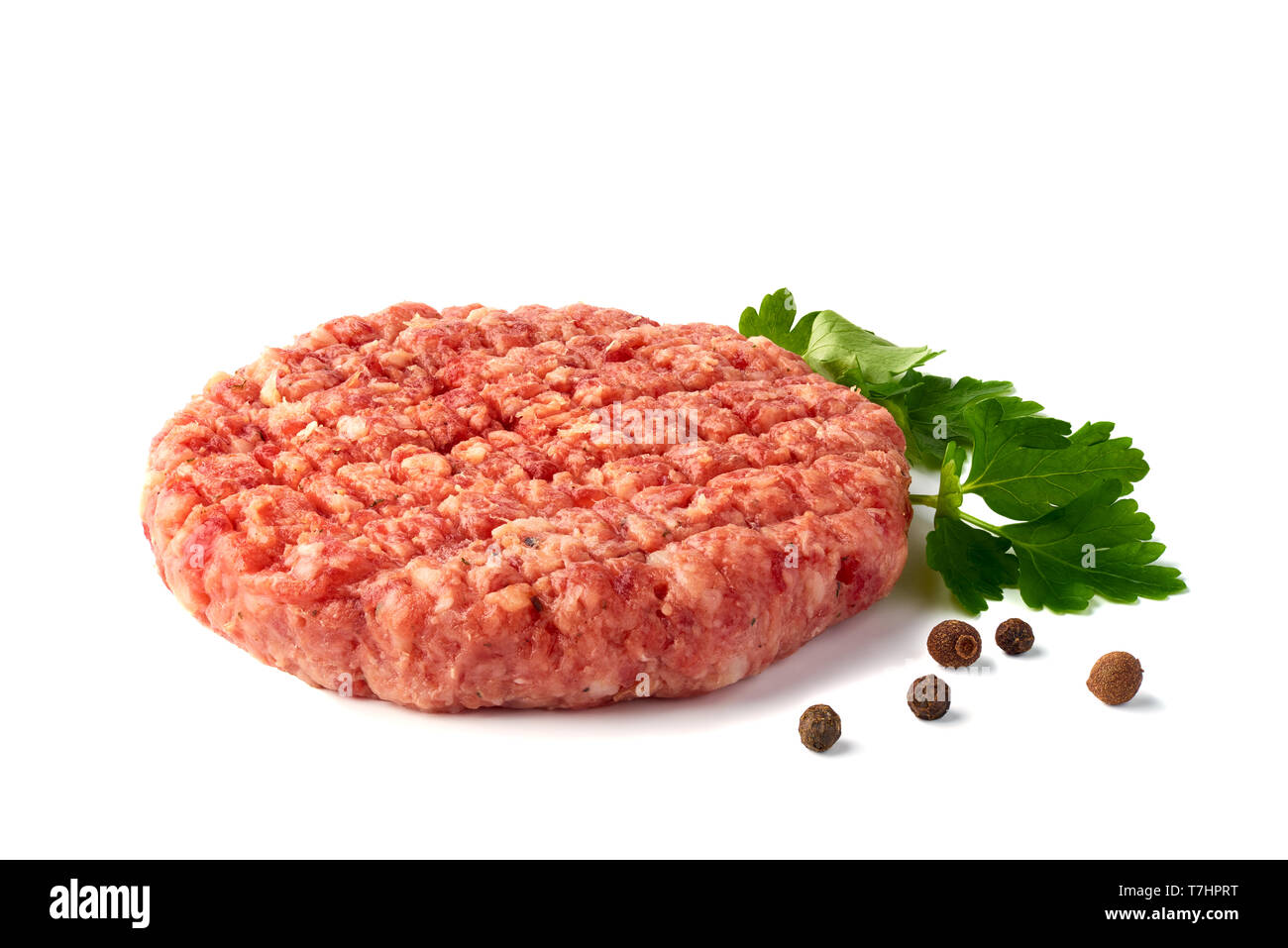 Rohes Rindfleisch Patty mit Gewürzen auf weißem Hintergrund Stockfoto