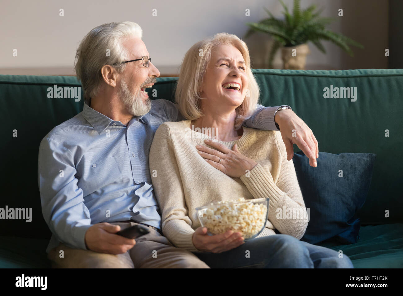 Lachen im Alter von Paar, Mann und Frau, Fernsehen und essen Popcorn Stockfoto