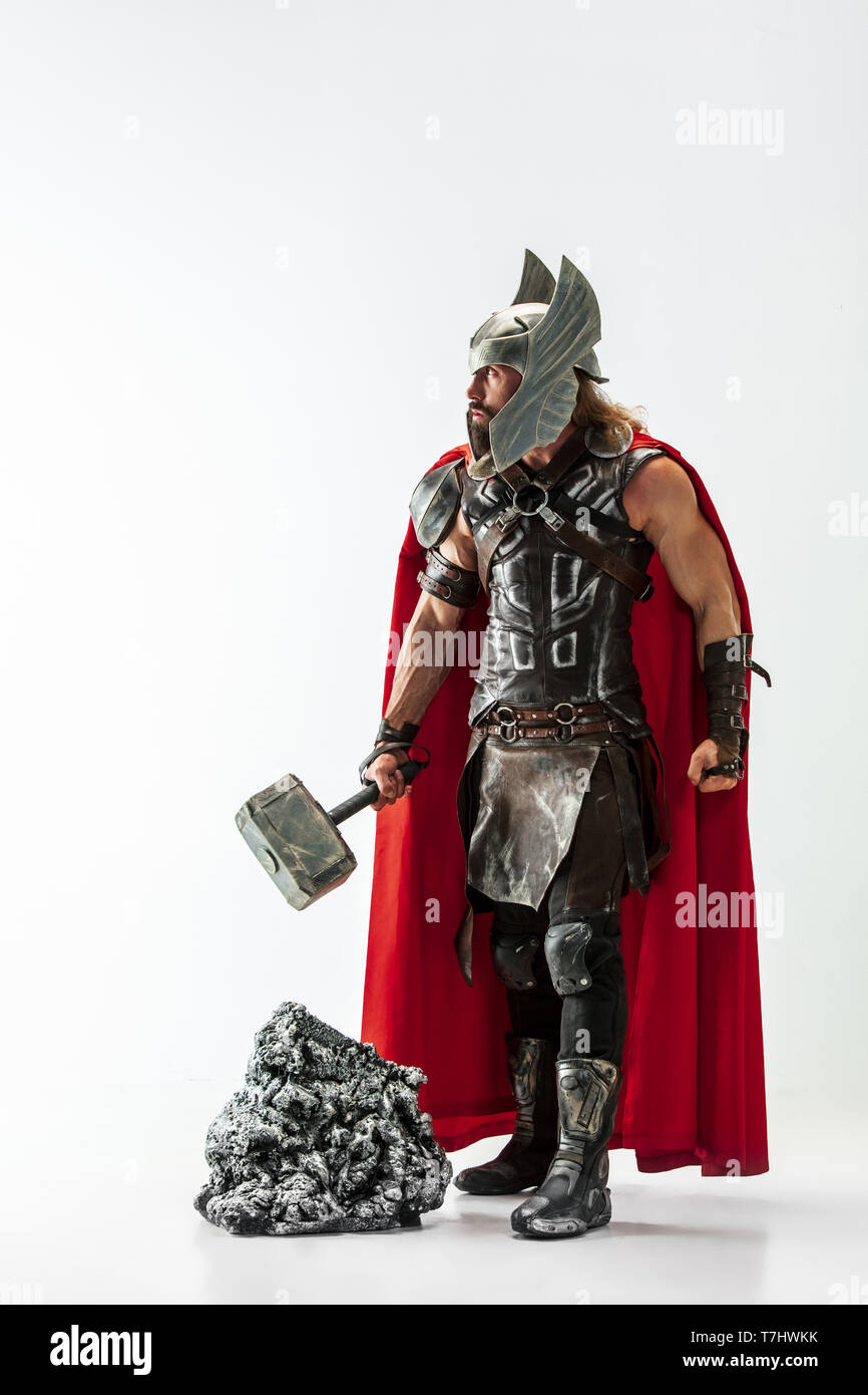 Langes Haar und muskulös männliches Modell in der Viking leder Kostüm mit dem großen Hammer cosplaying Thor auf weißem studio Hintergrund isoliert. In voller Länge Porträt. Fantasy Warrior, antiken Schlacht Konzept. Stockfoto