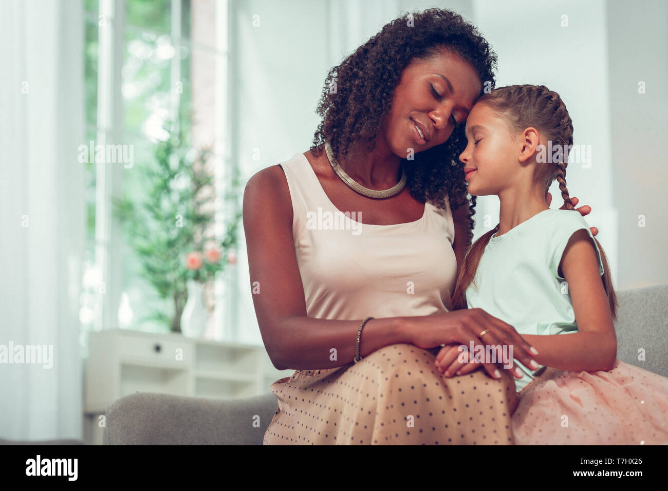 Süße kleine Tochter umarmte, von einem liebenden afroamerikanischen Mom. Stockfoto