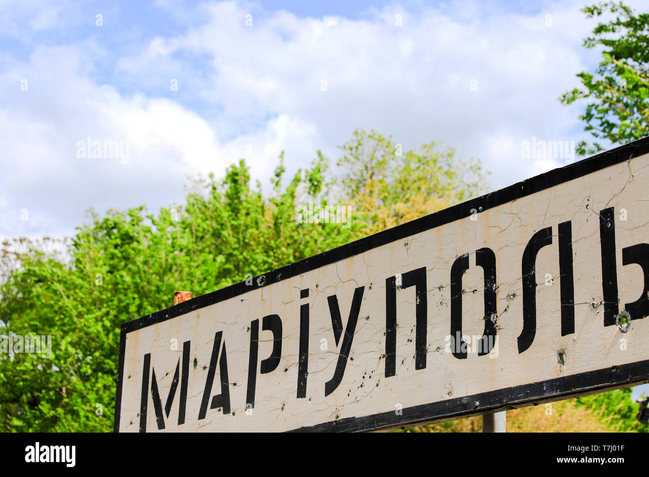 Schild mit der Inschrift in der ukrainischen Stadt Mariupol, der Region Donetsk, durch Kugeln, ukrainische Krieg, Donbass gelocht, Konflikt Osten der Ukraine Stockfoto