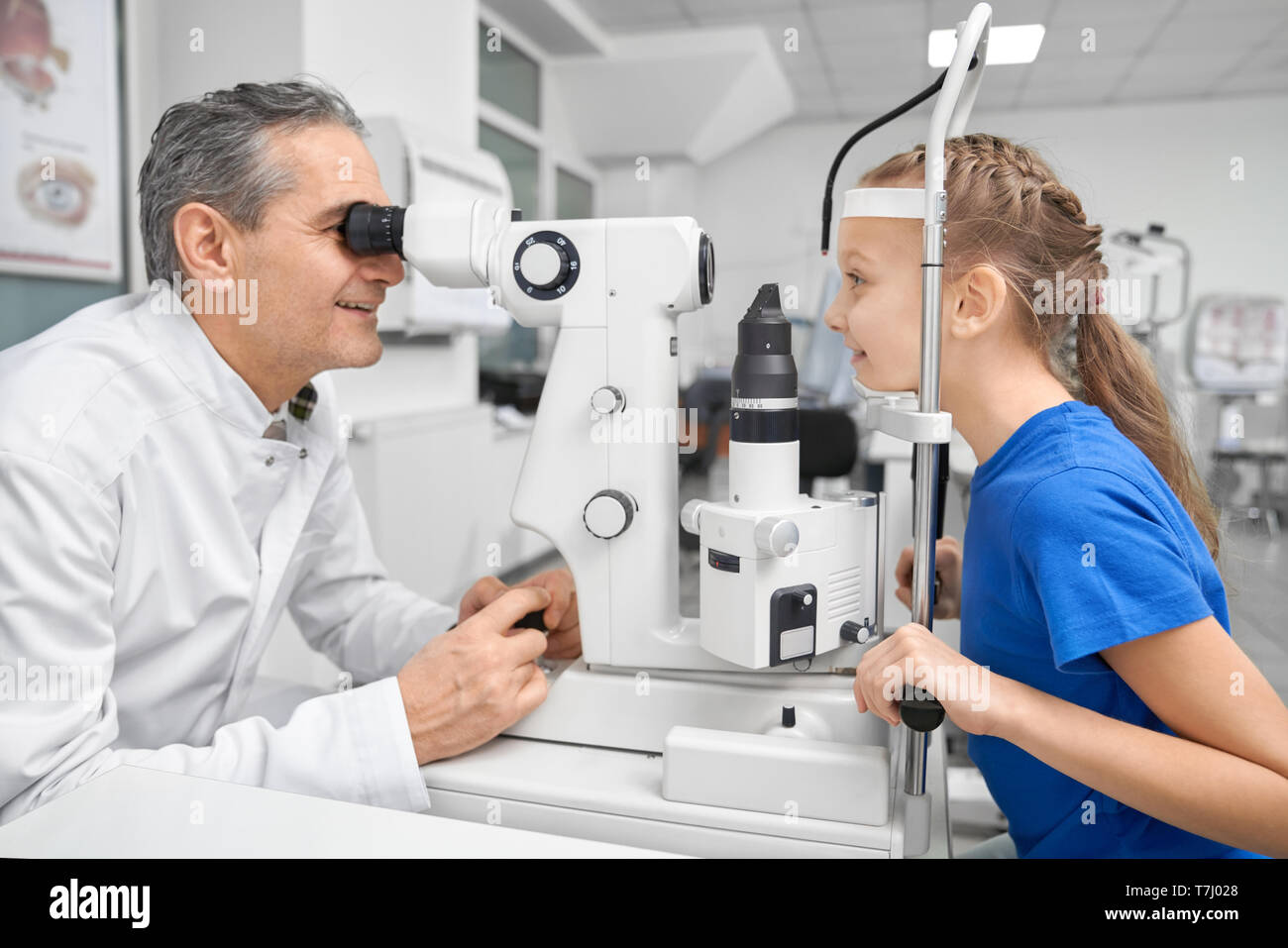 Professionelle Arzt Augenarzt die Augen des hübschen Patienten mit der spaltlampe. Augenarzt in Weiß medizinische Fell suchen durch spezielle Ausrüstung. Konzept der gesunden Sehkraft. Stockfoto