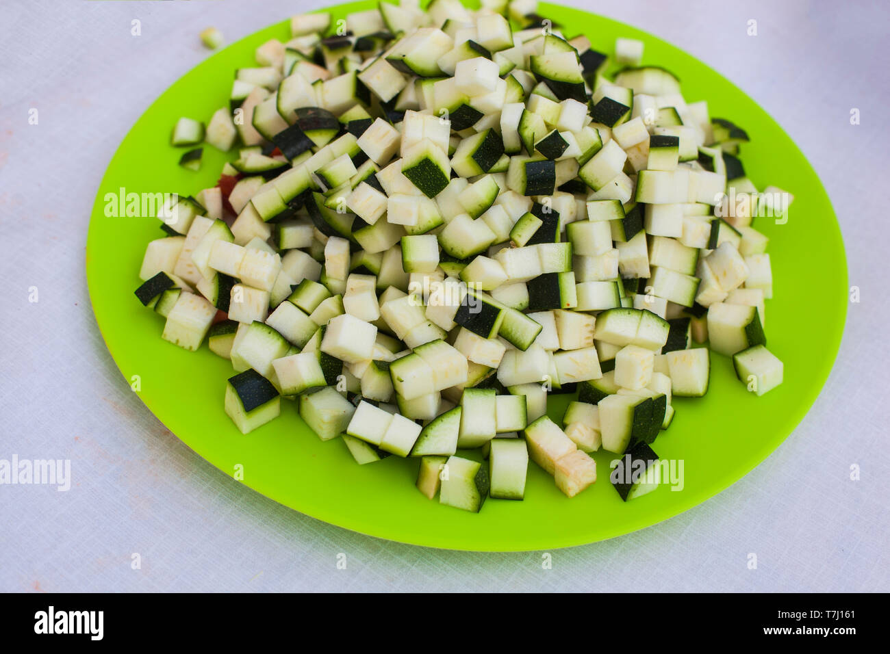 Eine grüne Platte voller Grün raw gewürfelte Zucchini bereit, in die Pfanne zu erhalten Stockfoto