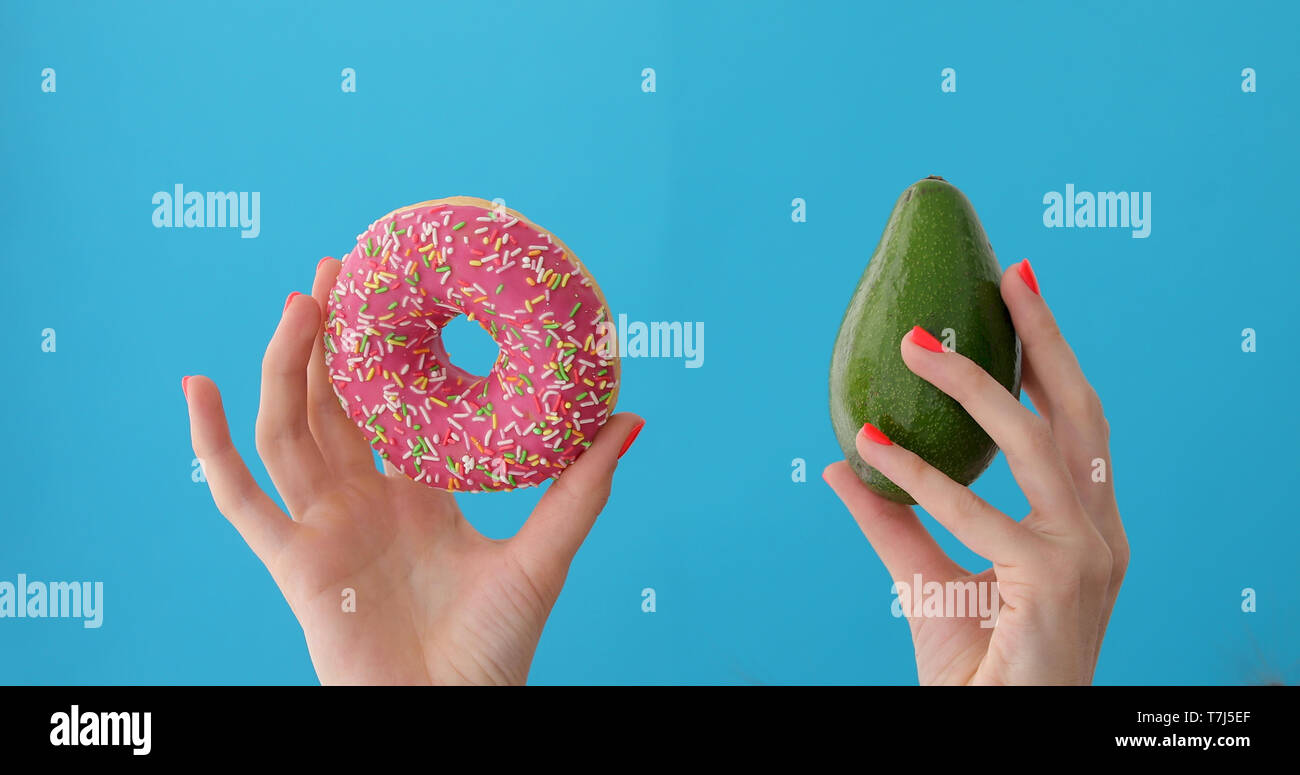 Hände, die Avocado und Donut Stockfoto