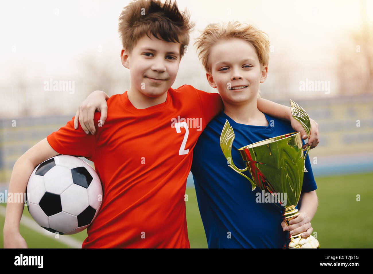 Zwei glücklichen jungen Fußball Spieler halten Fußball und goldene ...