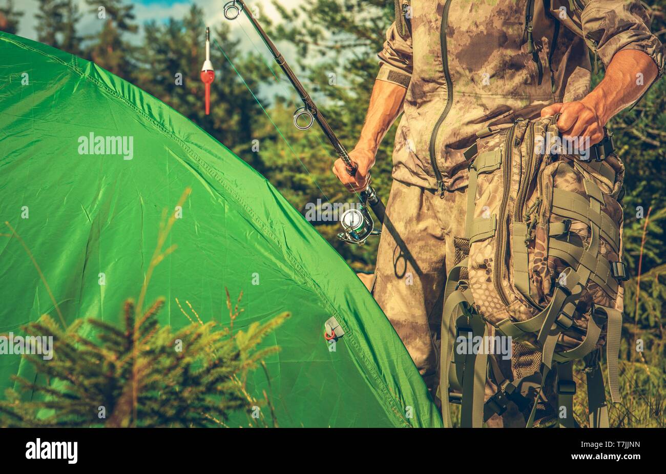 Fishing Camp Spot. Kaukasische Männer mit Angelrute vor seinem Zelt. Aktivitäten im Sommer. Stockfoto