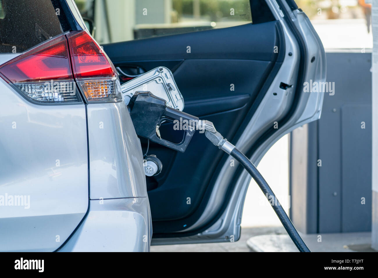 Auto befüllen Tank an einer Tankstelle, mit offener Tür Stockfoto