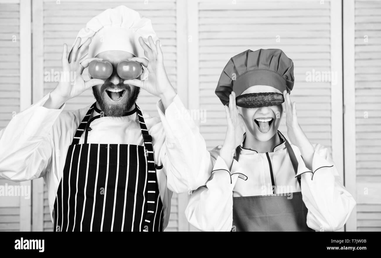Gesund gesund Ernährung. Master cook und Helfer spielen mit Gemüse in der Küche. Koch und Küche Zimmermädchen holding Tomaten und Gurken an Augen. Paar Köche Spaß mit natürlichen Essen im Restaurant. Stockfoto
