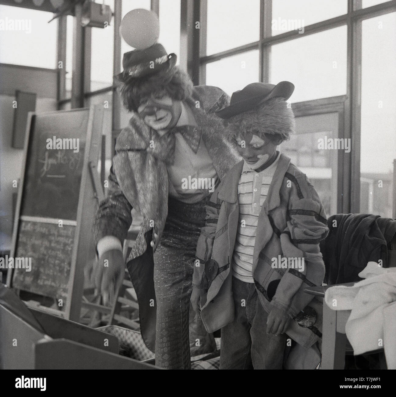 1960, historische, einem Zirkus Clown mit einem jungen Schüler auch bis und mit seinem Gesichter gemalt als Clown verkleidet, England, UK. Stockfoto