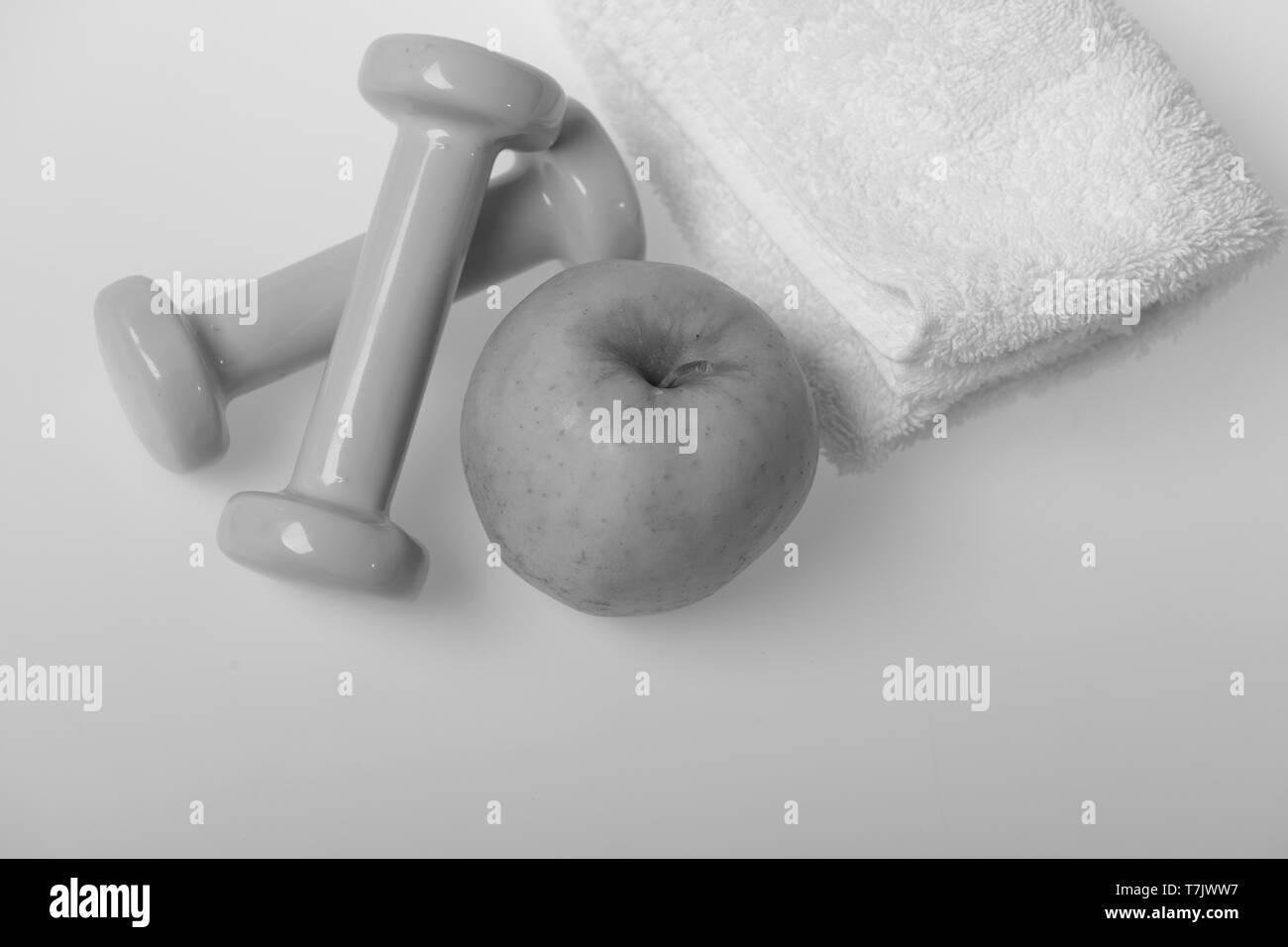 Barbells klein neben Apple Obst, Ansicht von oben. Hanteln aus Kunststoff blau in der Nähe von weichen Handtuch auf weißem Hintergrund. Gesunder Lebensstil und Sport Konzept. Gesundheit und Fitness Symbole Stockfoto