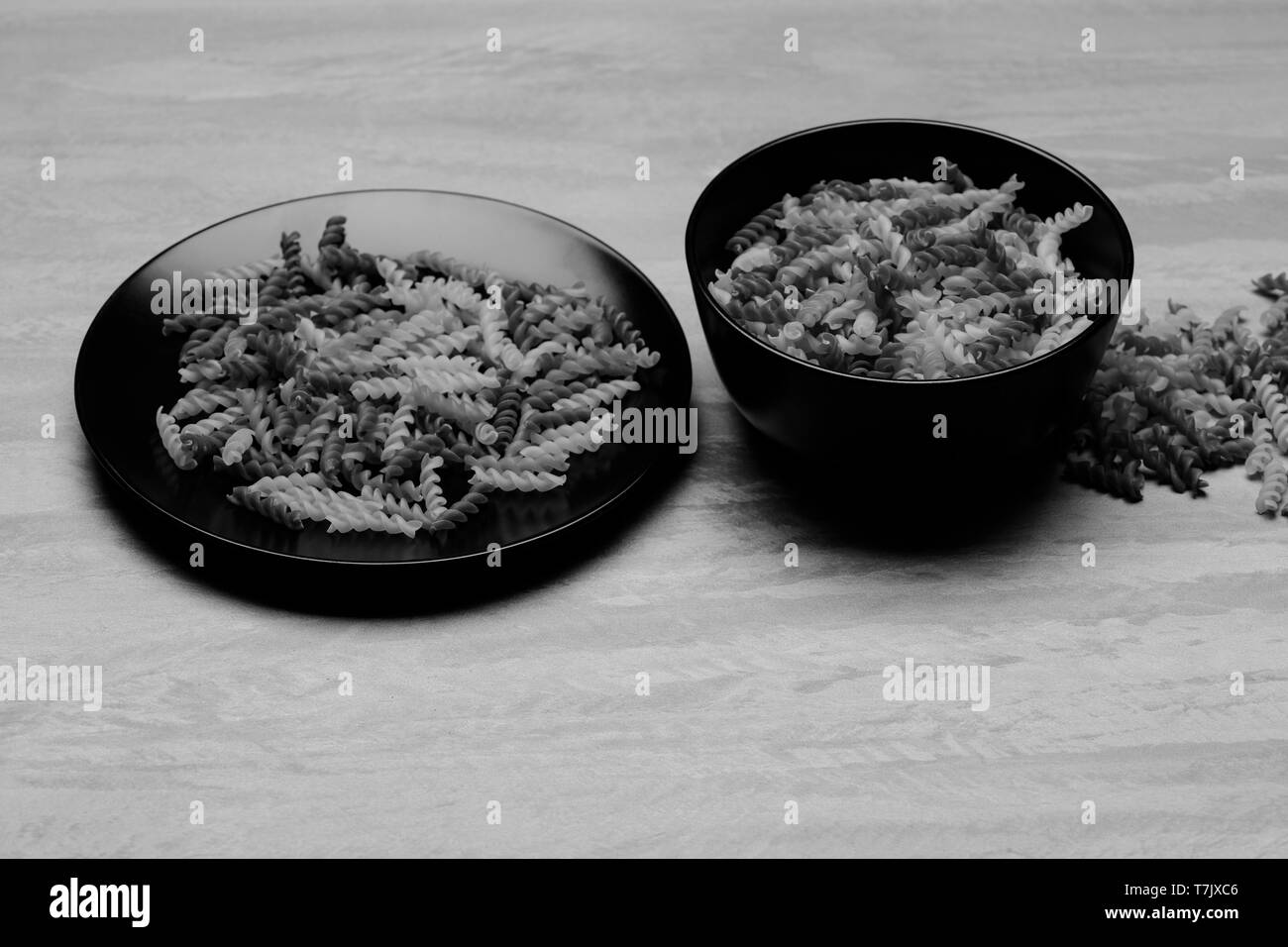 Leckere bunte Italienische Pasta in zwei schwarzen Keramikplatten auf Grau strukturierten Hintergrund, Seitenansicht Stockfoto