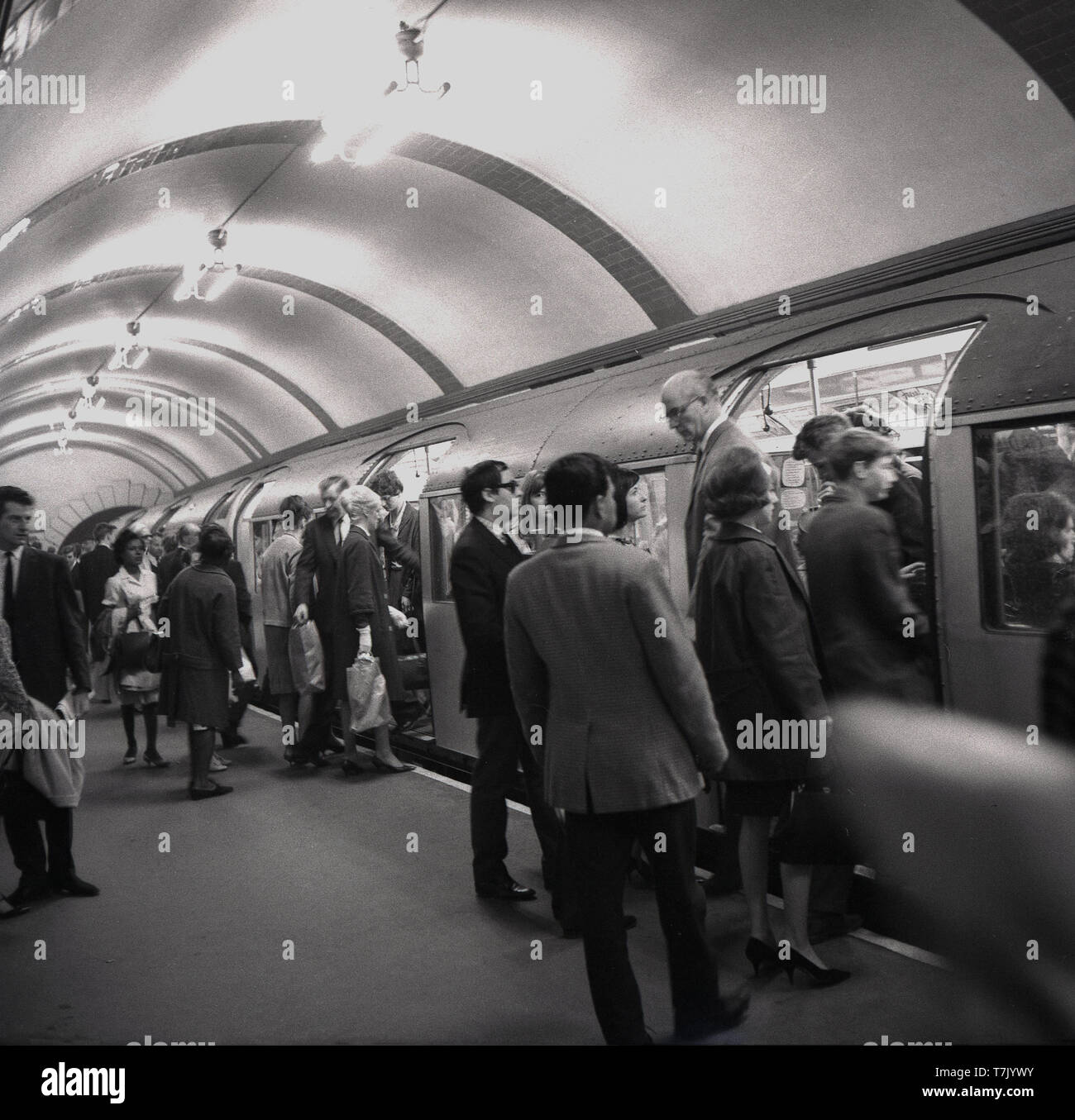 1960, historische, die Londoner U-Bahn, eine U-Bahn auf einer Plattform, die Menschen beim Ein- und Aussteigen, London, England, UK. Die orgins der Londoner U-Bahn liegen in der Metropolitan Railway, die erste U-Passagier Eisenbahn der Welt, die 1863 eröffnet wurde. Gas beleuchteten Holz- Wagen wurden von Dampf angetriebene Lokomotiven. Stockfoto