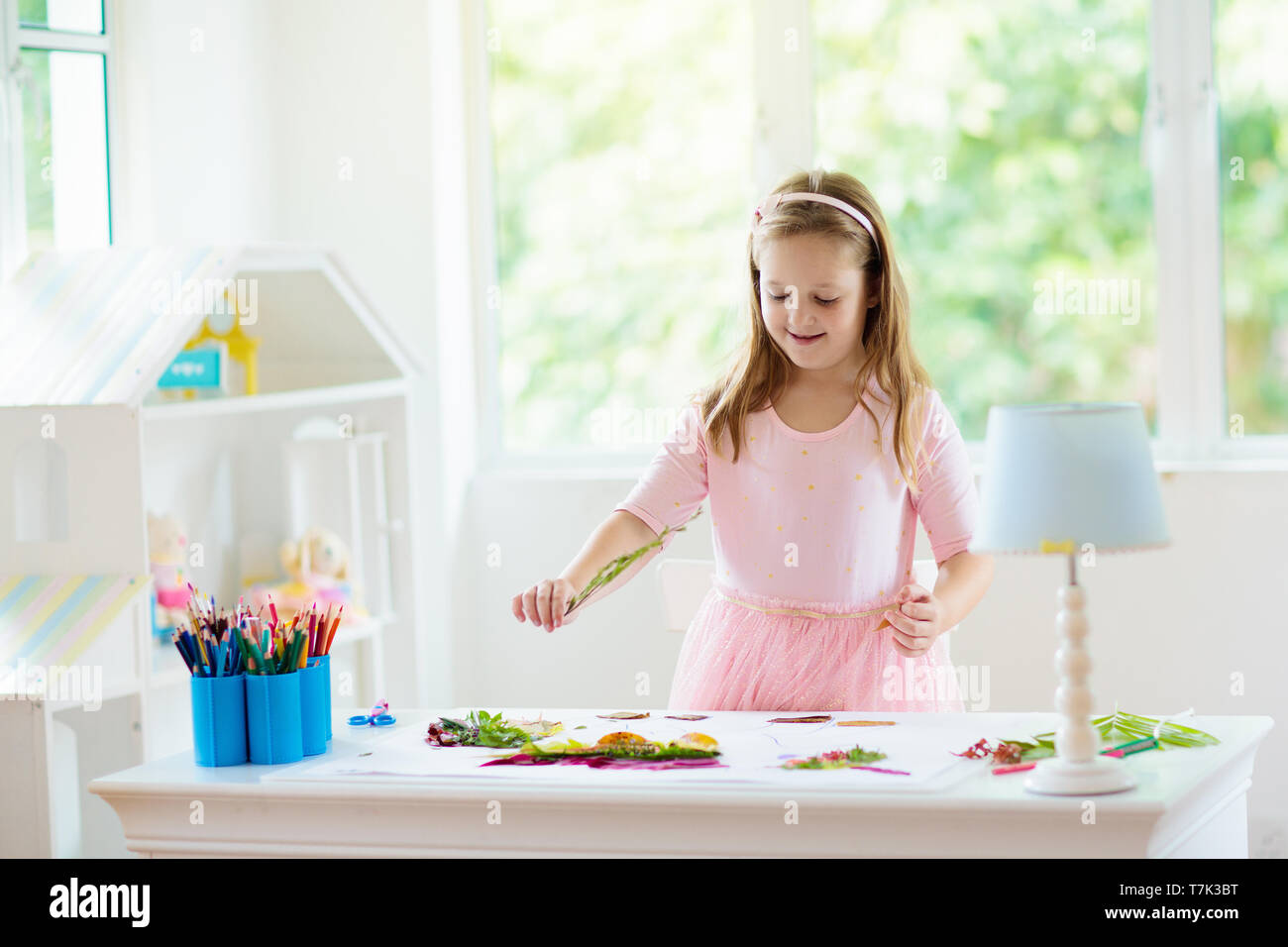 Kind erstellen Bild mit bunten Blättern. Kunst und Handwerk für Kinder. Kleines Mädchen, collage Bild mit Regenbogen pflanze Blatt. Biologie Hausaufgaben für y Stockfoto