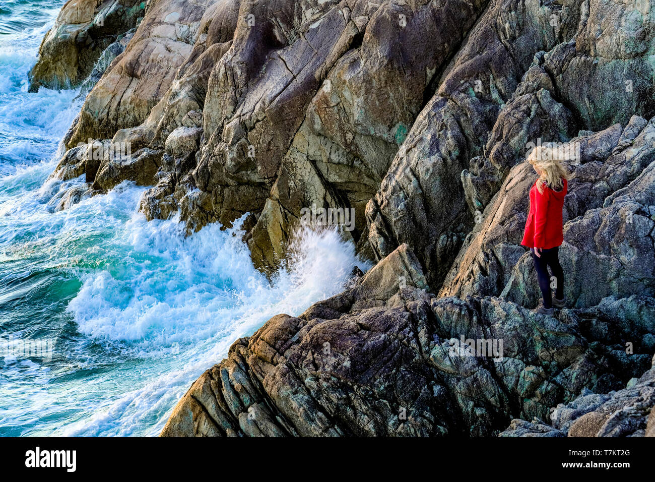 Blonde Frau auf Felsen und beobachtete, Wellen, Lighthouse Park, West Vancouver, British Columbia, Kanada Stockfoto