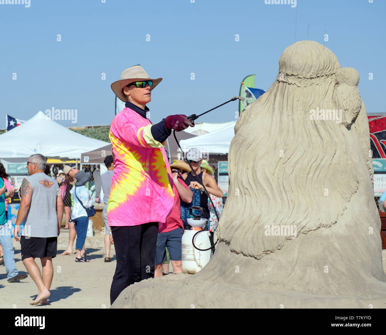 Remy Hoggard sprays Befeuchtungslösung auf ihrem Platz 3 & People's Choice Award winning Skulptur ofia, "Texas Sandfest 2019, Port Aransas, Texas USA. Stockfoto