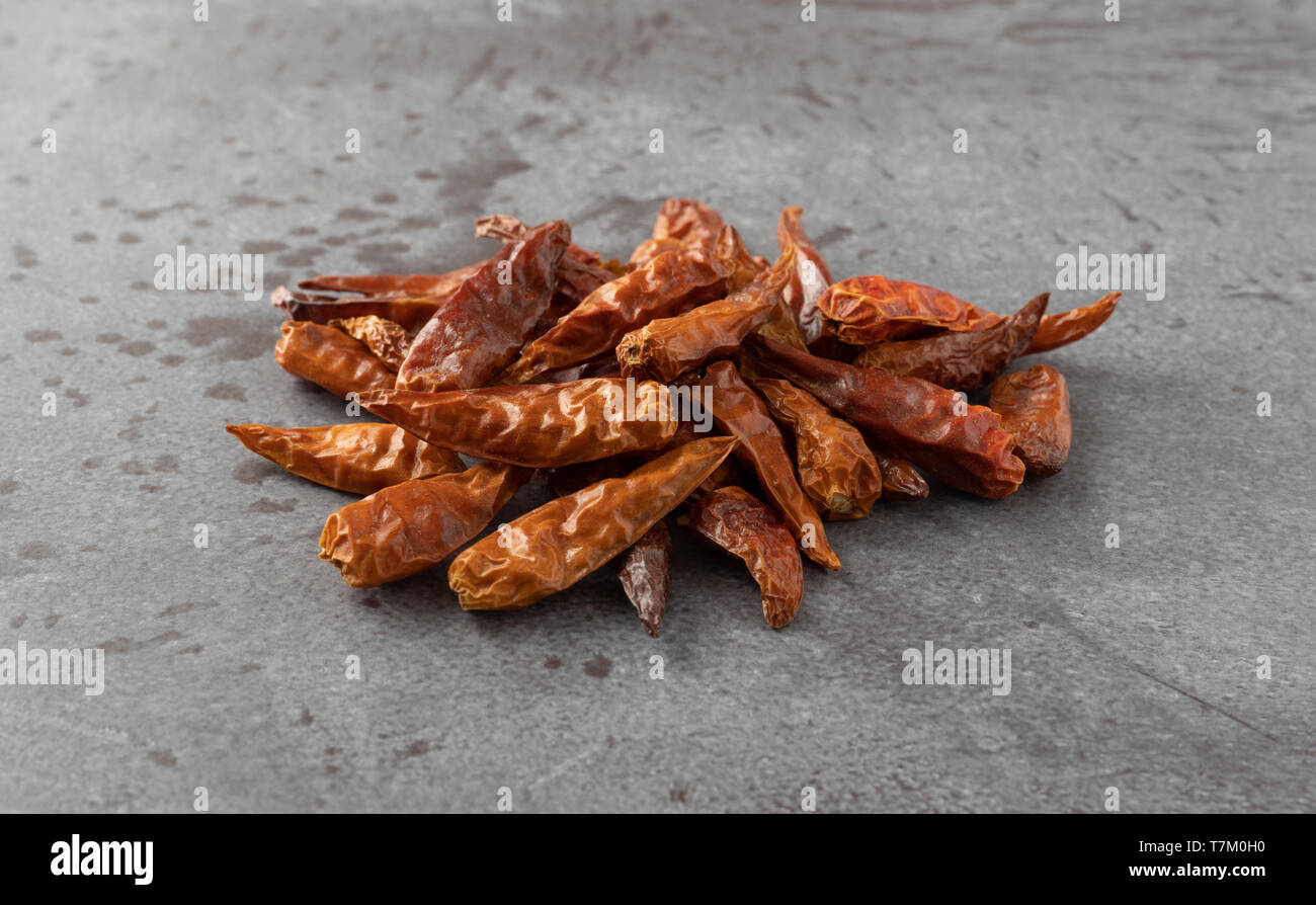 Seitliche Sicht auf einen Teil der getrockneten Vietnamesischen chili peppers auf grauem Hintergrund mit natürlichem Licht beleuchtet. Stockfoto
