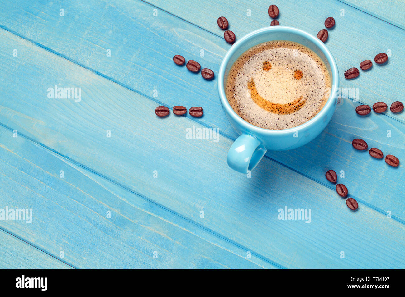 Kaffeetasse mit Smiley auf Blau Holztisch Stockfoto