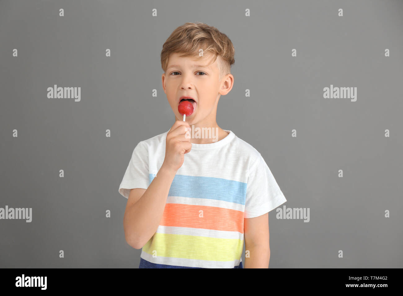 Cute little boy mit Lollipop auf grauem Hintergrund Stockfoto