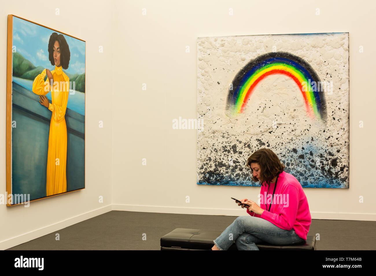 New York, NY-Mai 3, 2019. Eine Frau auf dem Telefon entspricht einem Regenbogen Farbe in ein Gemälde von New York's Hälfte Galerie auf der Frieze Art Fair in New York City's Randalls Island dargestellt. Stockfoto