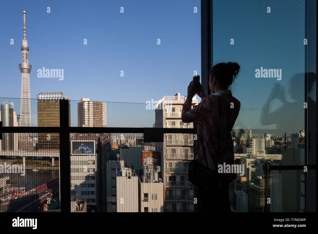 Eine weibliche Touristin fotografiert den Tokyo Skytree vom Dach der Asakusa Tourist Information. Tokio, Japan. Stockfoto