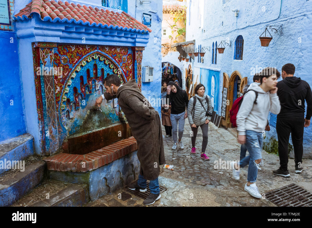 Chefchaouen, Marokko: Ein Marokkaner Getränke Wasser aus einem Brunnen im Blau getünchte Medina, Altstadt. Stockfoto