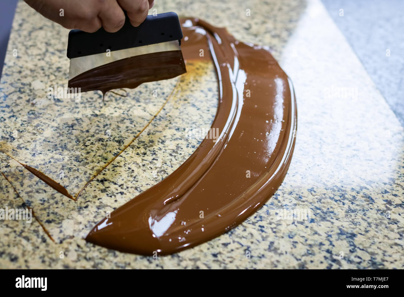 Chocolatier rührt die temperierte Schokolade auf einem Klapptisch, die zur Kühlung Stockfoto