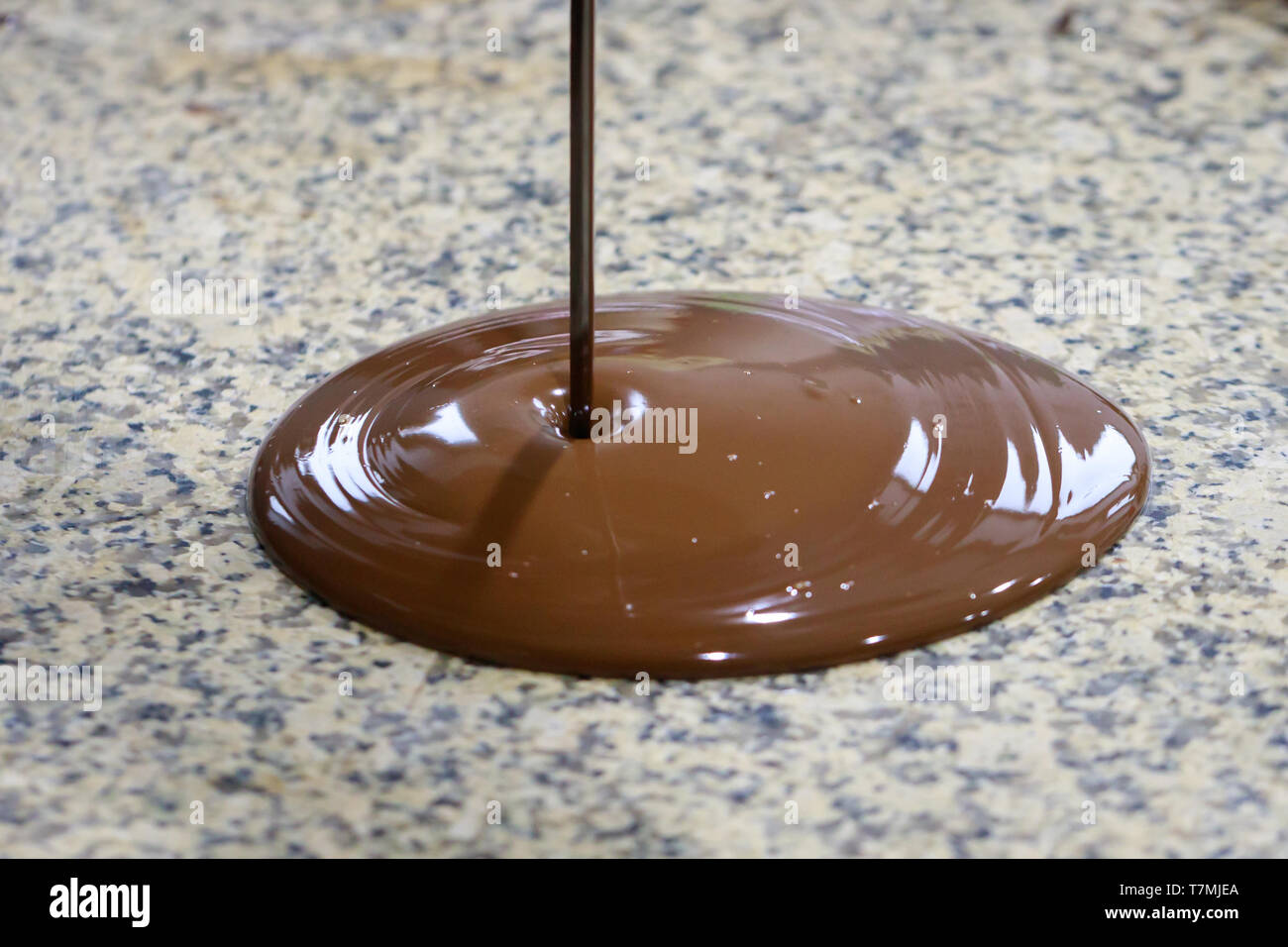 Flüssige Schokolade ist auf einem Granit Tisch gegossen. Close-up Stockfoto
