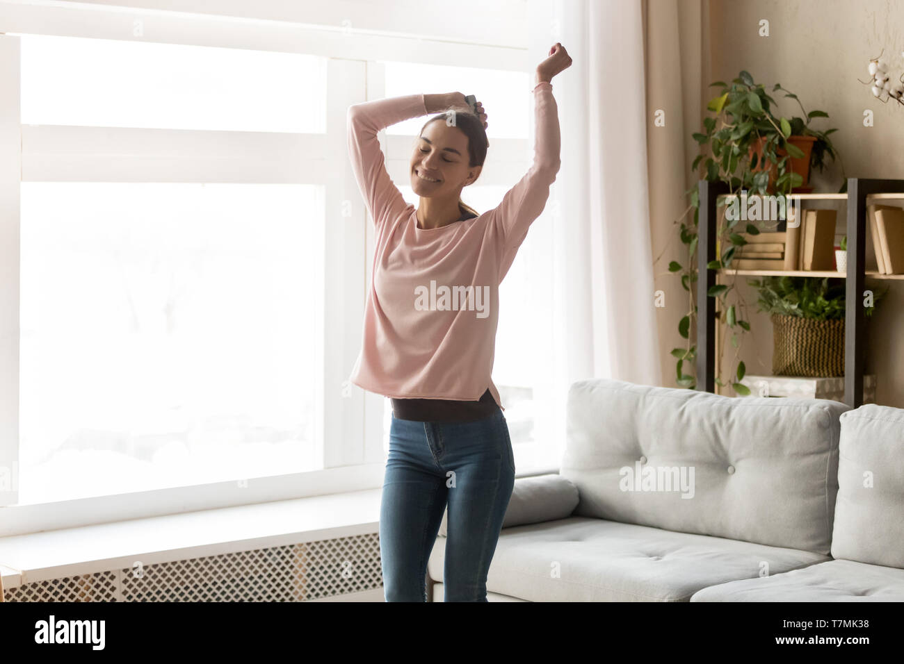 Sorglos attraktives Mädchen tanzen im Wohnzimmer zu Hause Stockfoto