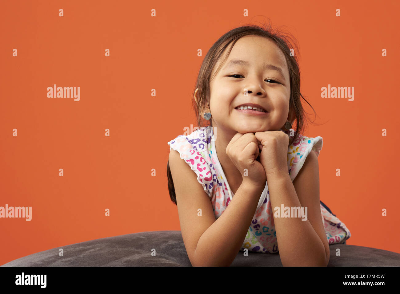 Asiatische Kind auf einem Sitzsack in einer Farbe Hintergrund posiert. Filipina kid entspannend. Stockfoto
