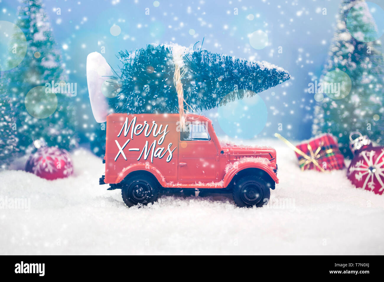 Tannen und Miniatur oldtimer Spielzeugauto mit Schnee und Schneeflocken Frohe Weihnachten Stockfoto