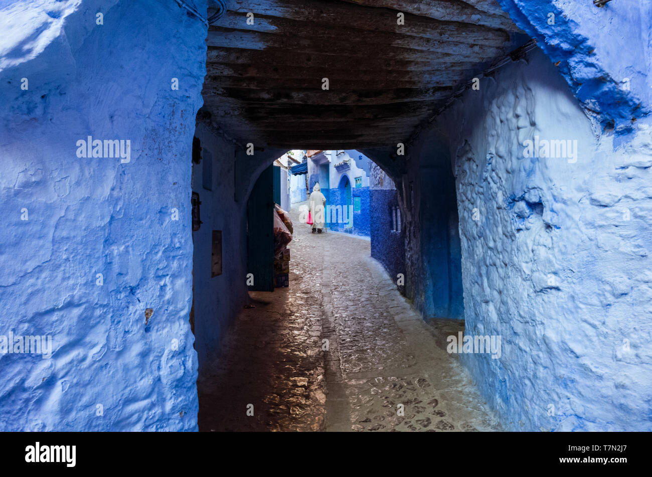 Chefchaouen, Marokko: ein Mann mit einem trational djellaba Spaziergänge in die Gassen der Blau getünchte Medina, Altstadt. Stockfoto