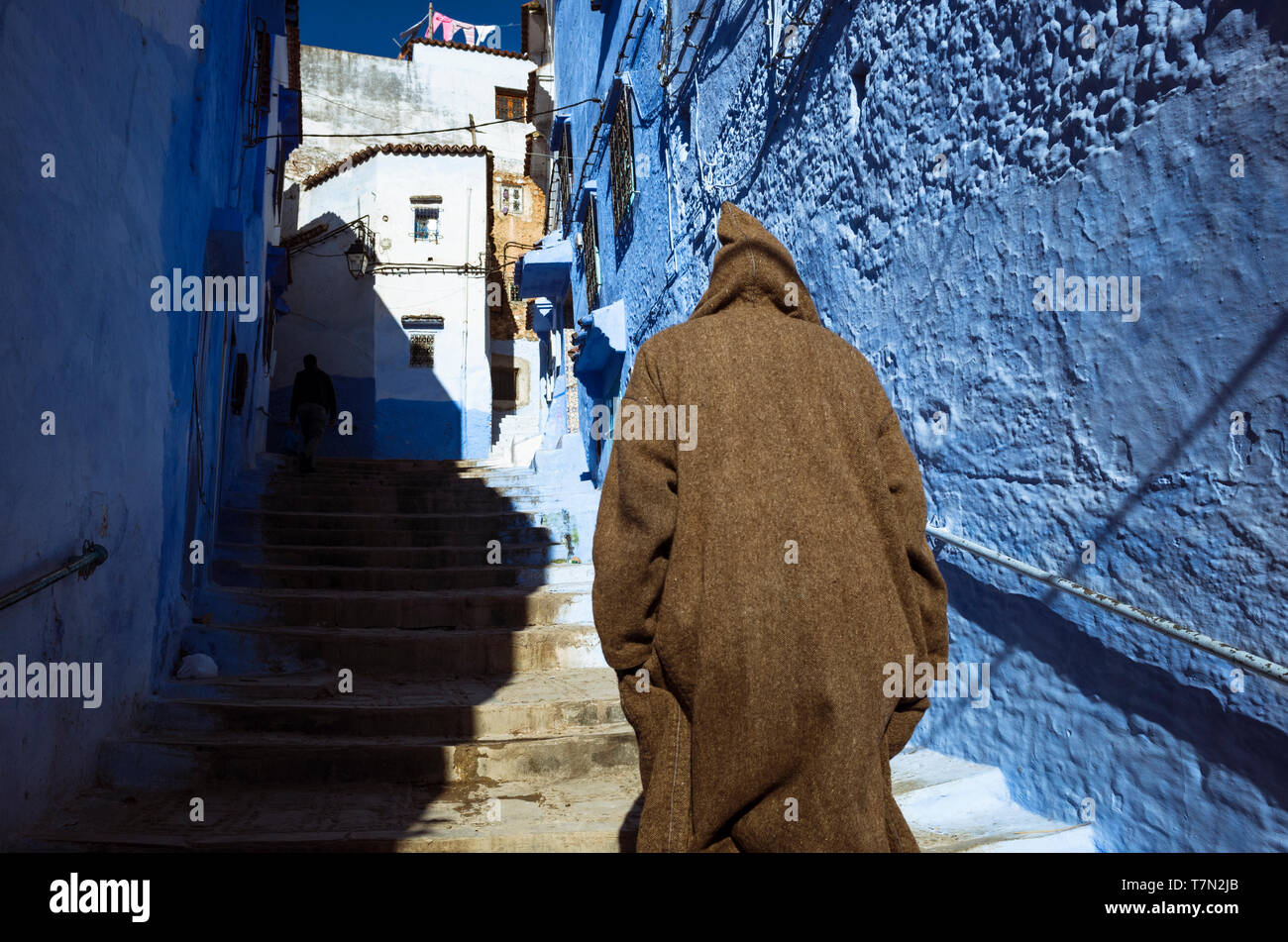 Chefchaouen, Marokko: ein Mann mit einem trational djellaba Spaziergänge in die Gassen der Blau getünchte Medina, Altstadt. Stockfoto