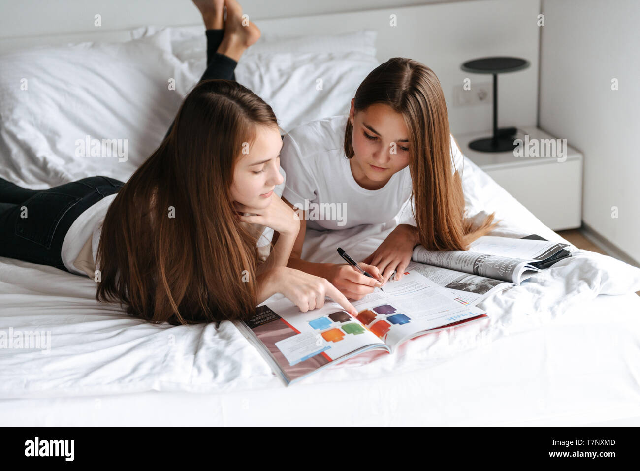 Zwei freundliche junge jugendmädchen Festlegung auf dem Bett, lesen Magazin Stockfoto