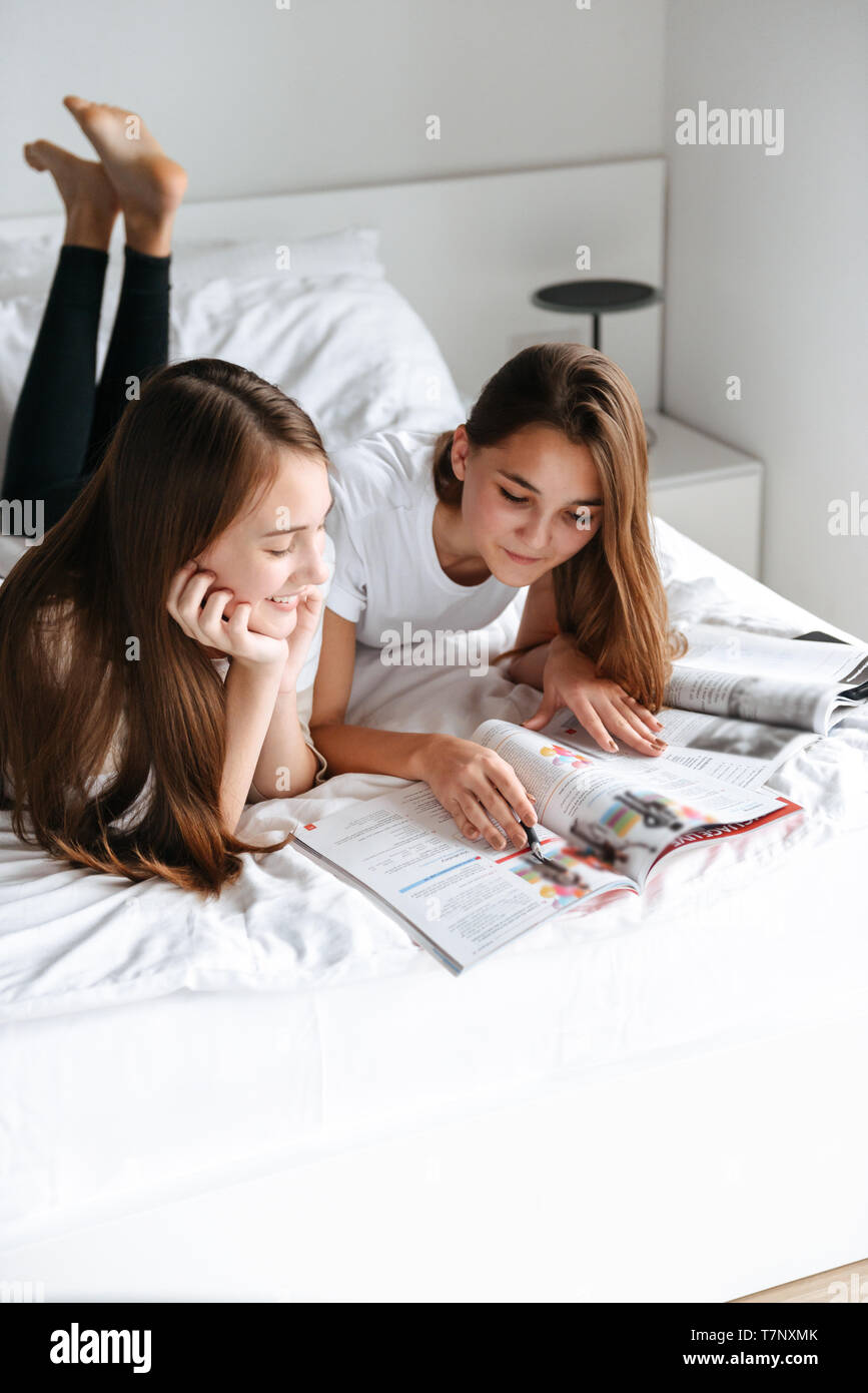 Zwei freundliche junge jugendmädchen Festlegung auf dem Bett, lesen Magazin Stockfoto