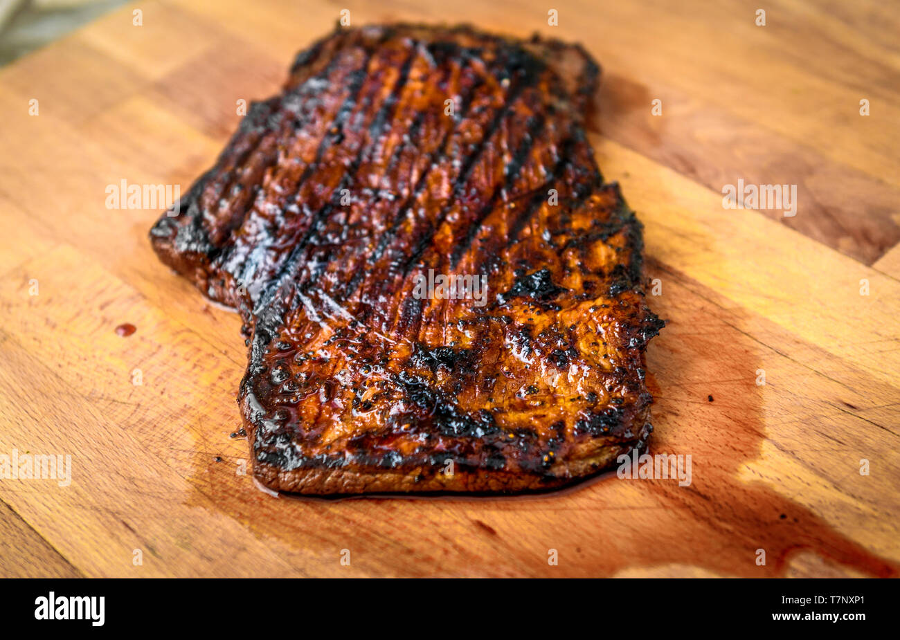 Saftig gegrillte marinierte Angus Beef Flank Steak auf Holzbrett. Fertige saftige medium Fleisch ruht, bevor es geschnitten ist und in Scheiben geschnitten. Stockfoto