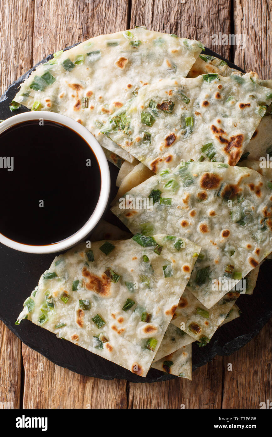 Grüne Zwiebel Pfannkuchen sind eine schmackhafte chinesische Fladenbrot einfach gemacht mit Mehl, Wasser, Salz und gehackten Frühlingszwiebeln close-up auf einem Brett. Vertikale Ansicht von oben Stockfoto