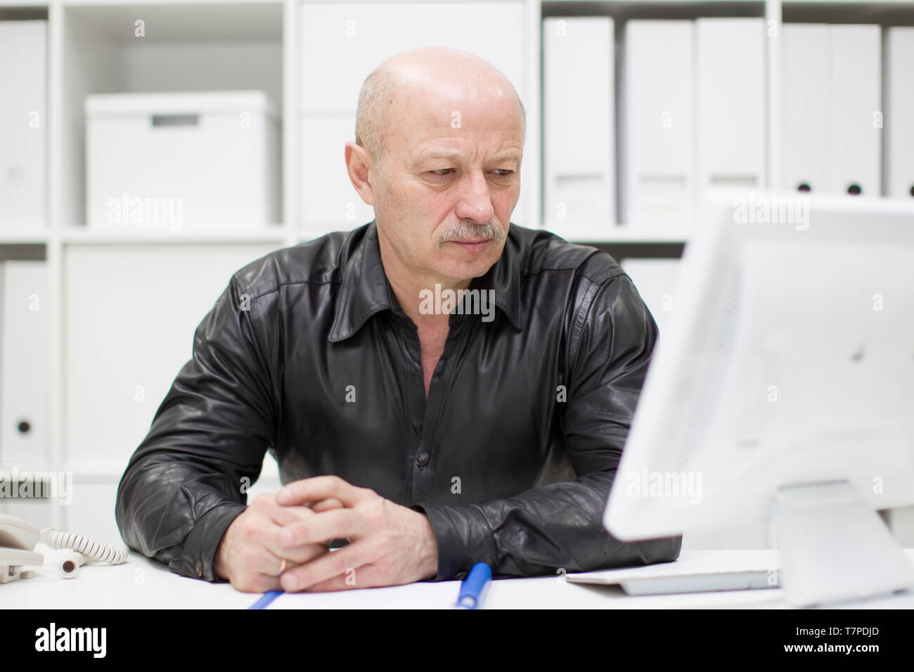 Ein älterer Mann mit Glatze am Computer. Rentner am Arbeitsplatz Stockfoto