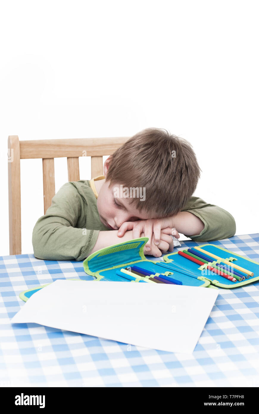 Ein Junge Kind müde und kämpfen mit den Belastungen des schriftliche Hausaufgaben. Stockfoto
