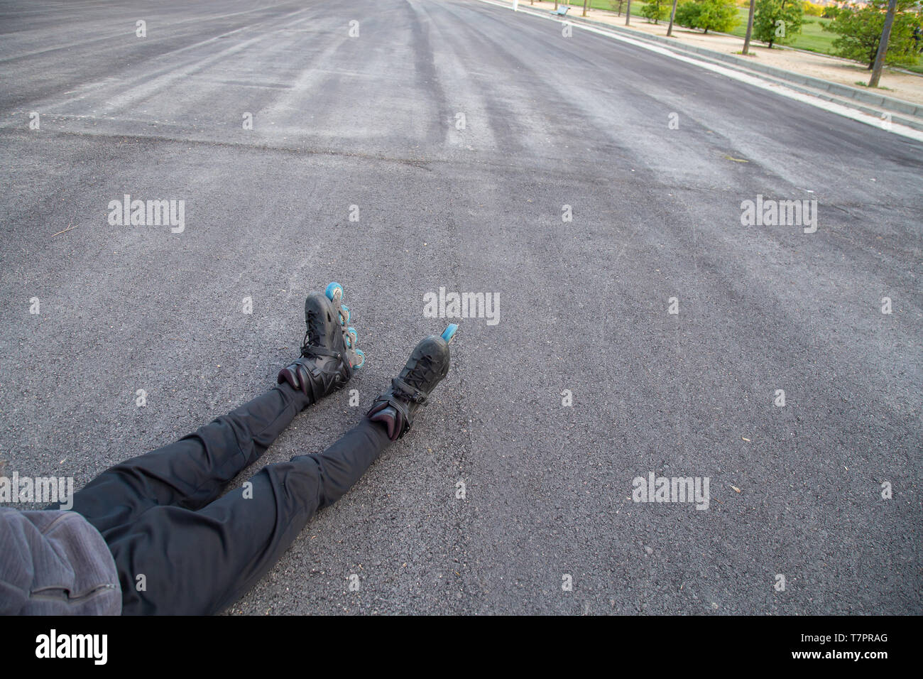 Von oben Jungen müde passen Mann in Sportswear mit Rollschuhen liegen auf der Straße Erntegut und Entspannend Stockfoto